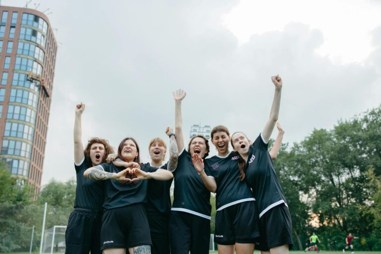 A joyful group of women soccer players celebrating victory on the field.