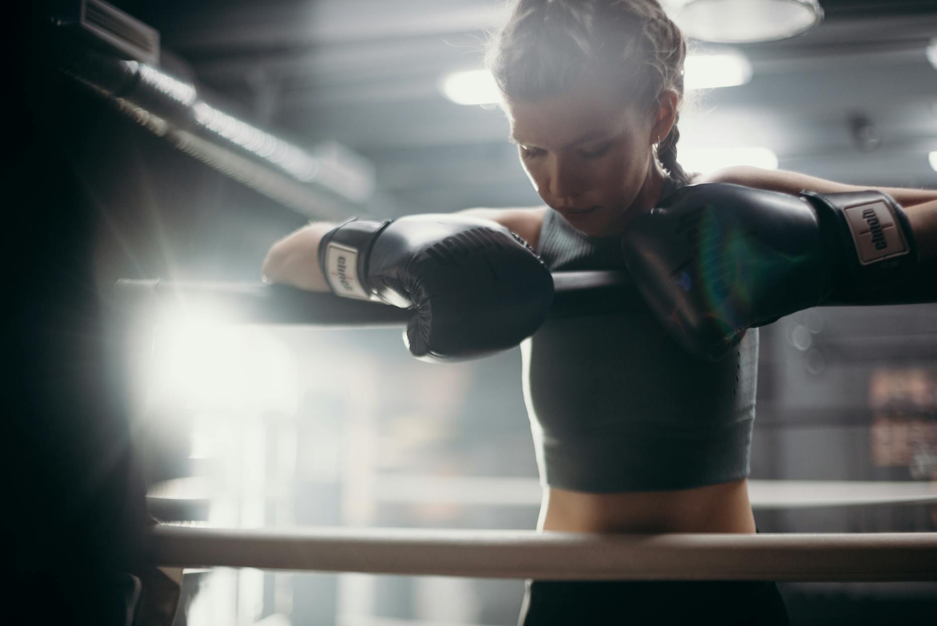 Young female boxer resting during an intense gym training session.