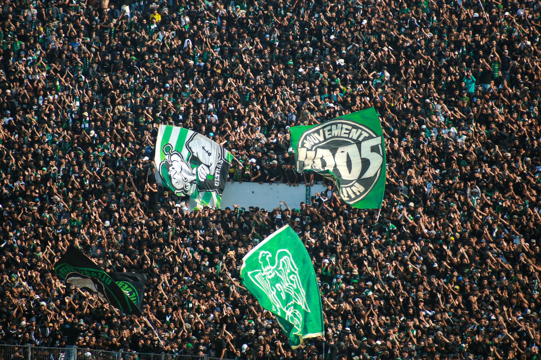Energetic crowd waving flags at a Raja Casablanca football match in Morocco.