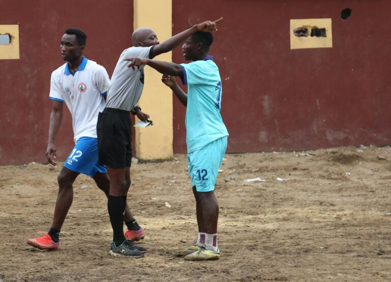 Soccer players and referee in heated discussion during a local match, highlighting sportsmanship.