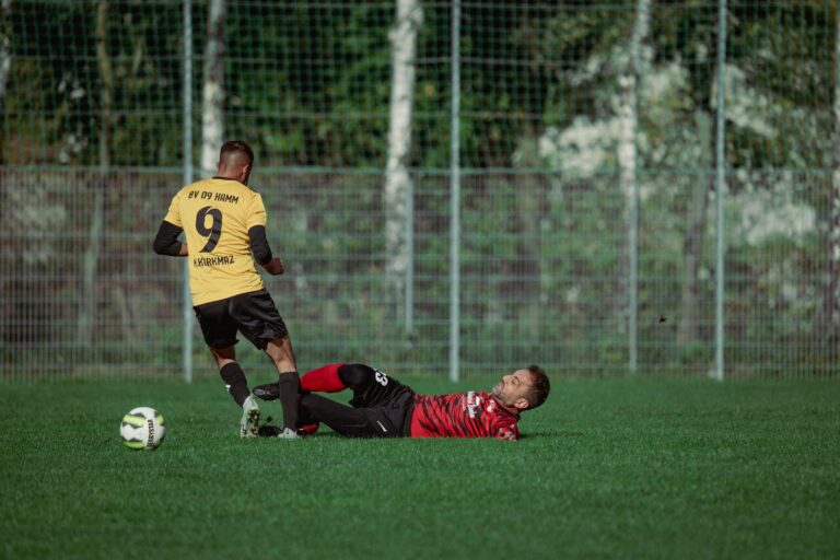 Two soccer players in action with a dramatic tackle on a grassy field during a match.