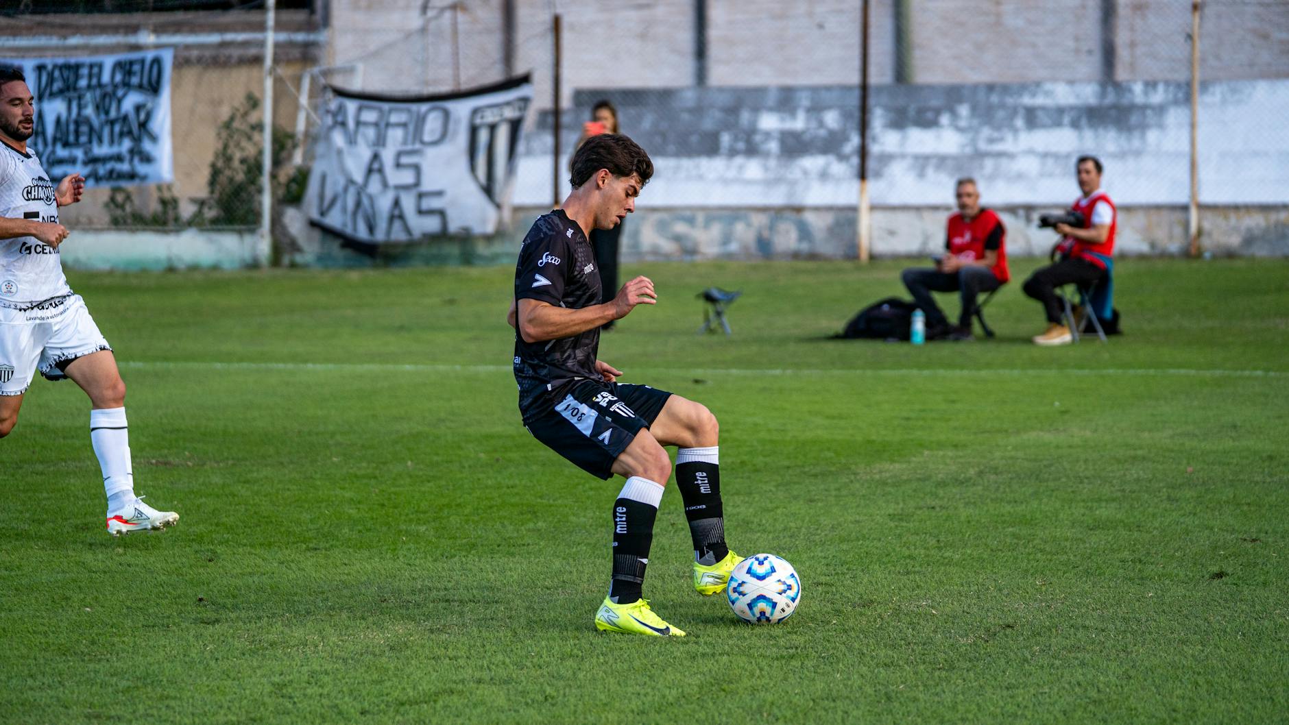 Dynamic shot of a soccer player controlling the ball during an outdoor match on a green field.