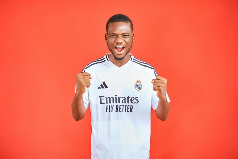 Energetic soccer fan in a team jersey cheering against a vibrant red background.