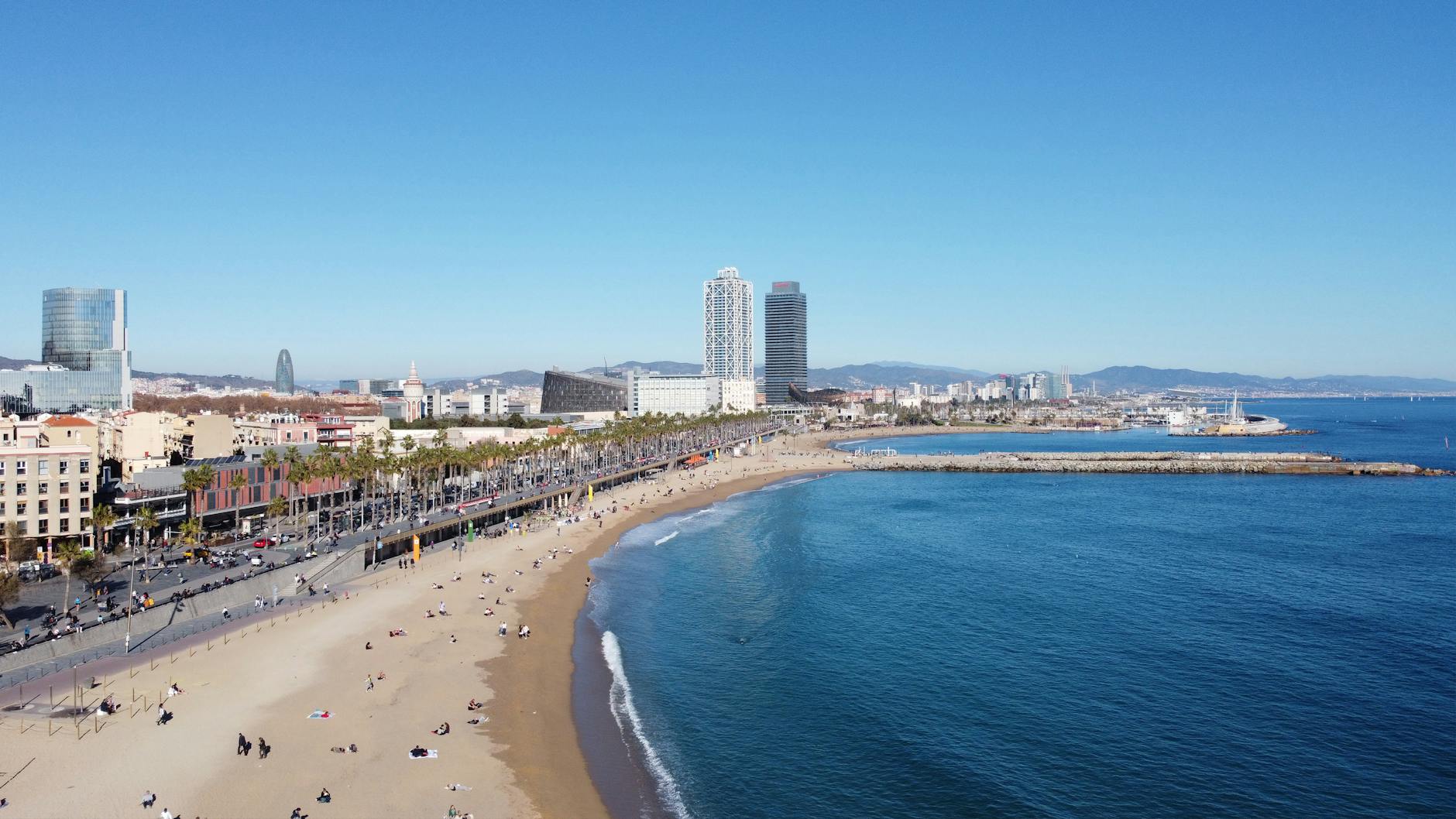 A stunning aerial shot of Barcelona's beach and city skyline on a clear day, capturing the vibrant coast.