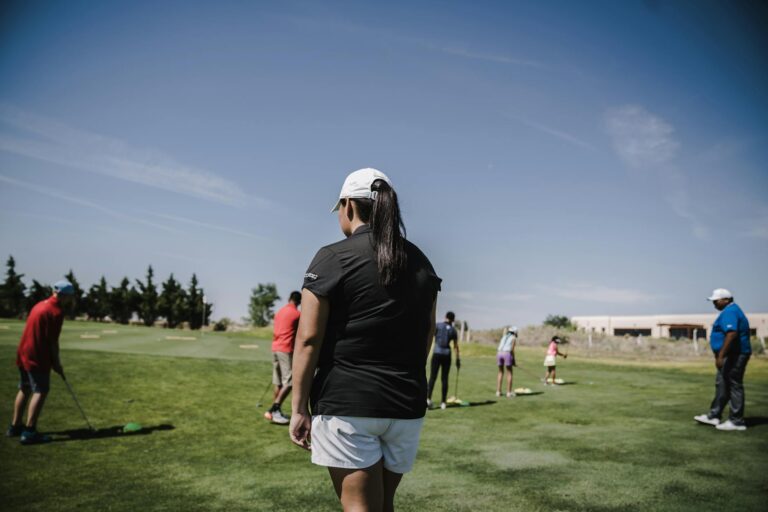 People enjoying a golf lesson on a bright day at the course.