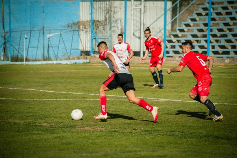 Athletes compete in a lively soccer match on a sunny day in Mendoza, Argentina.