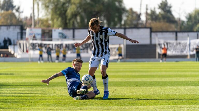Two soccer players battle for the ball during a competitive outdoor match.
