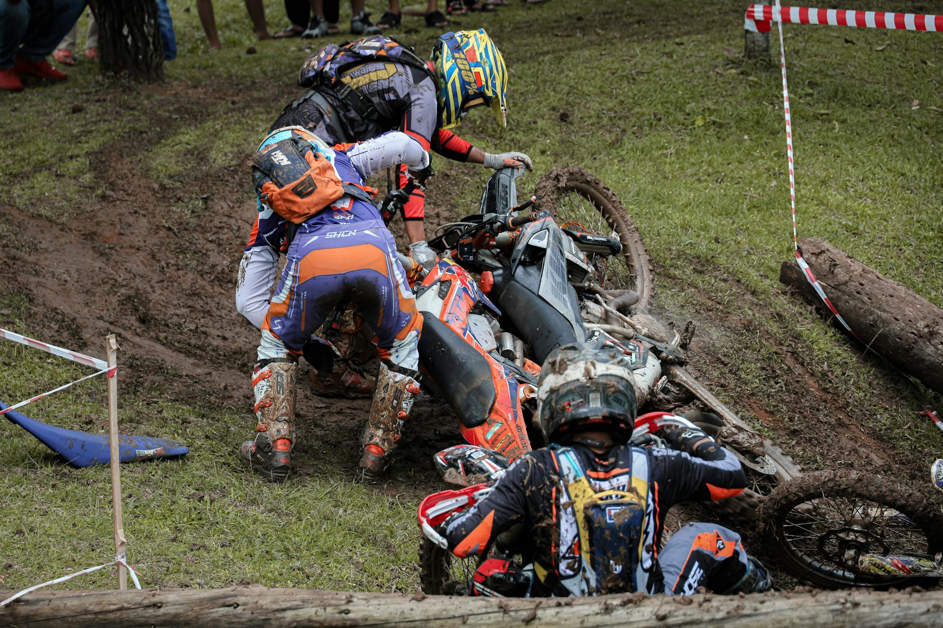 Three riders involved in a motorcycle accident on a muddy track in Bandung, Indonesia.