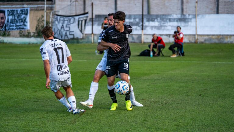 Two soccer players competing intensely on a green field during a daytime match.