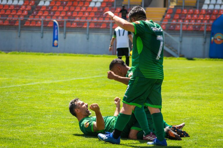 Dynamic shot of soccer players celebrating a goal during a daytime match.