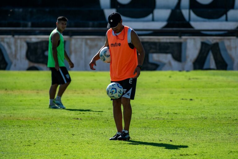 Two soccer players practice on a grassy field, one controlling the ball with skill.