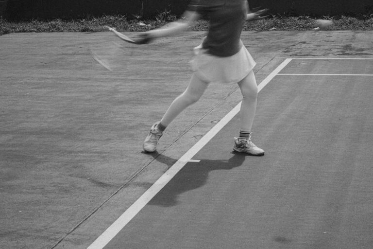 Black and white image of a person playing tennis with a blurred motion effect.