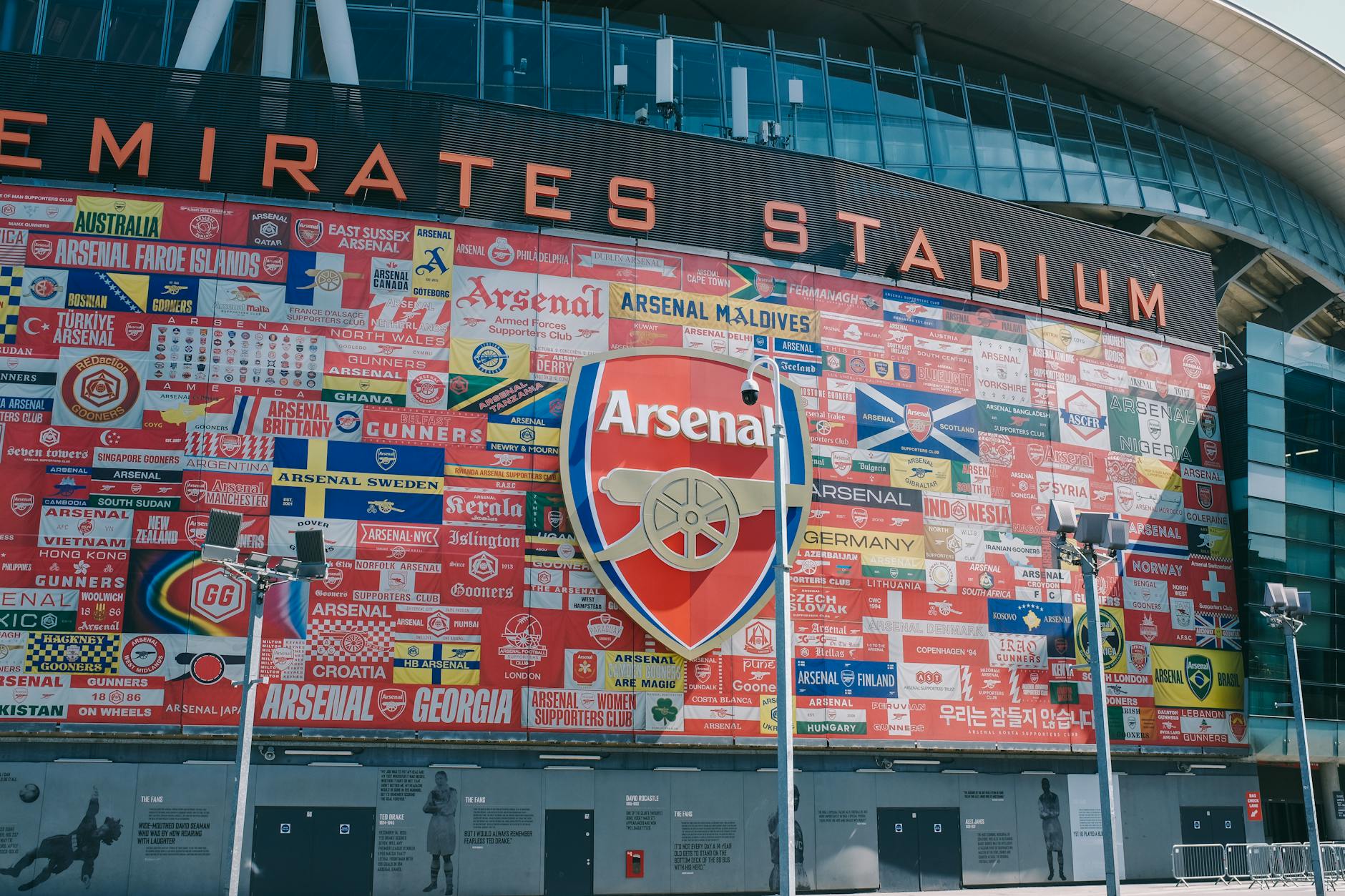 Vibrant wall art at Emirates Stadium featuring Arsenal flags and crest in London, UK.