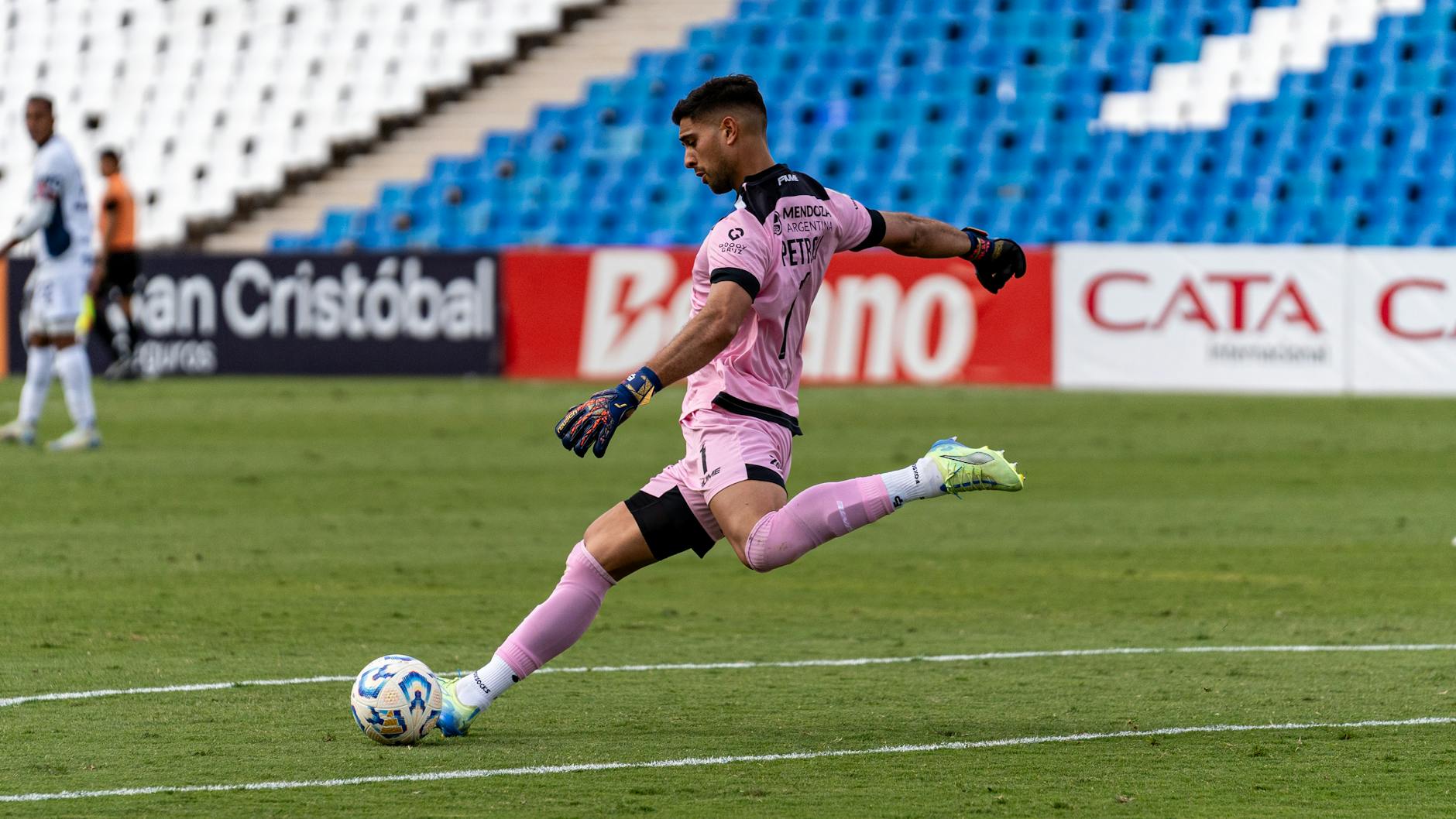 Dynamic shot of a goalkeeper in pink uniform kicking a soccer ball.