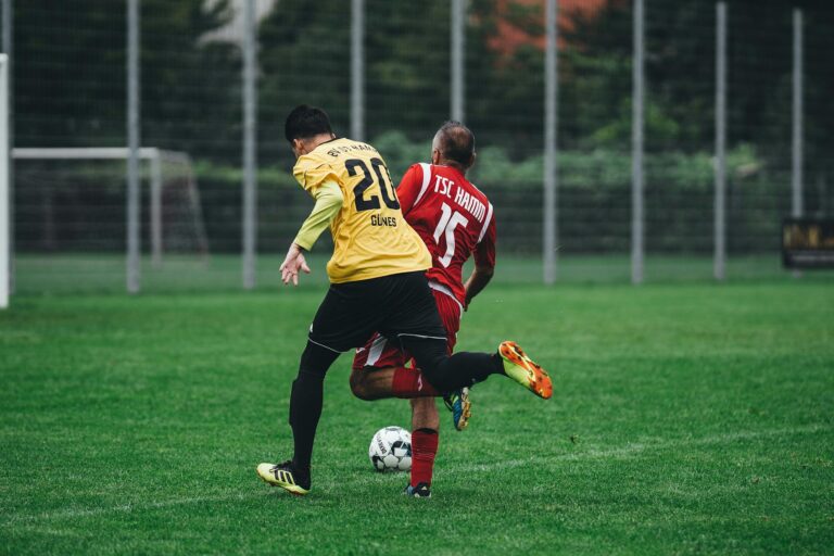 Two soccer players in action on a vibrant green field during a daytime match.