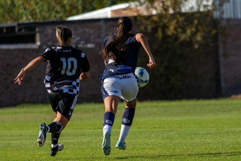 Exciting capture of two female soccer players in action on the field during a sunny day.