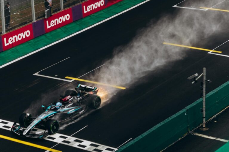 Dynamic shot of a Formula 1 car speeding across a wet track creating a spray of water.