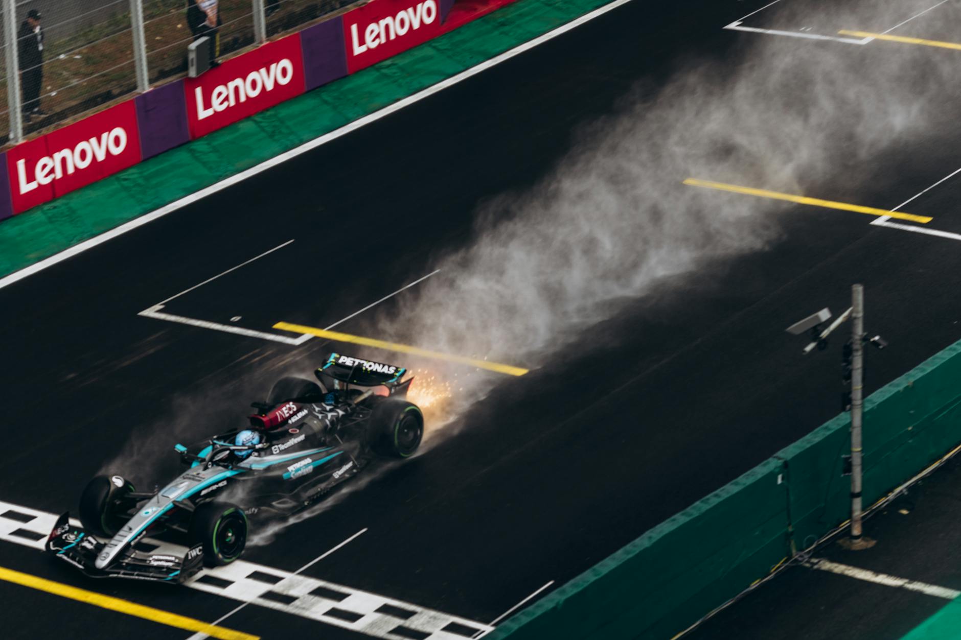Dynamic shot of a Formula 1 car speeding across a wet track creating a spray of water.