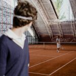 Tennis players on an indoor clay court during a competitive match.