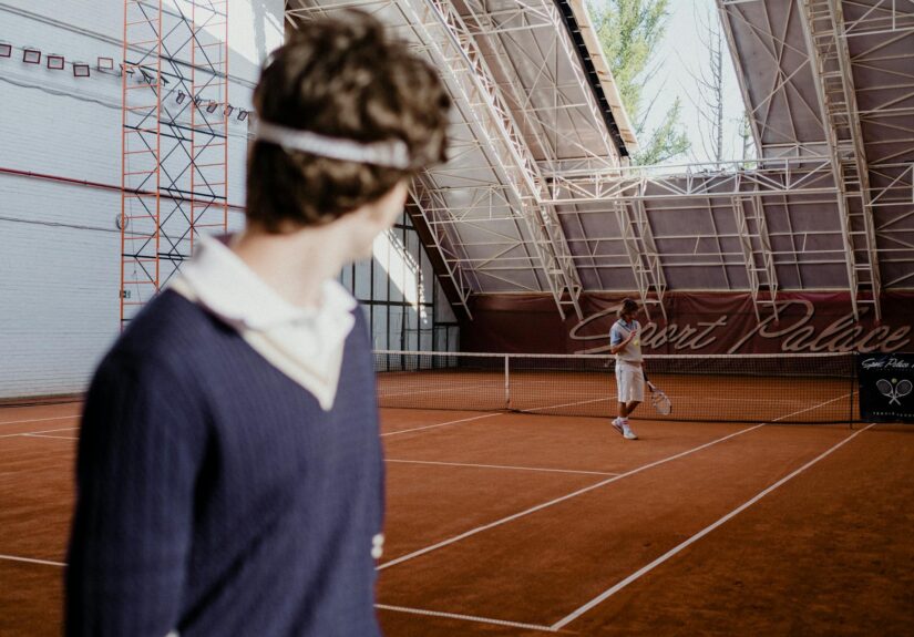 Tennis players on an indoor clay court during a competitive match.