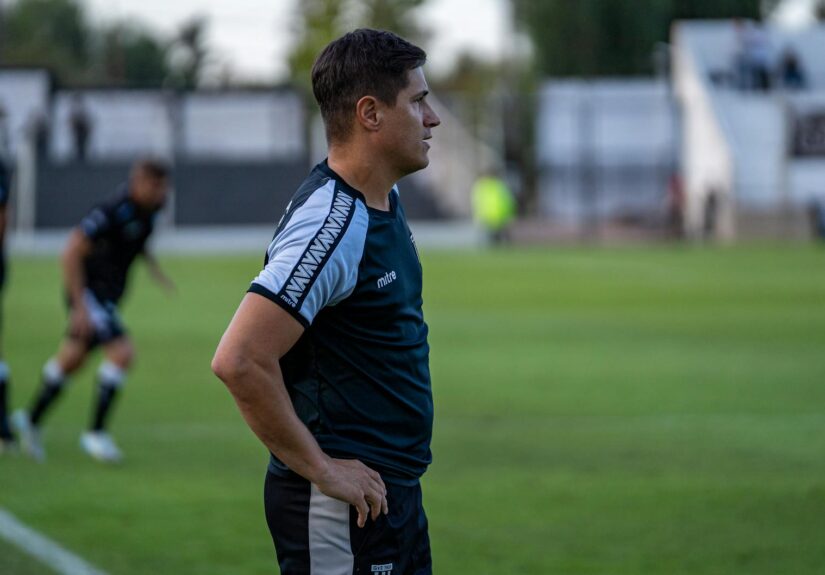 Soccer coach observing match strategy during an outdoor game.