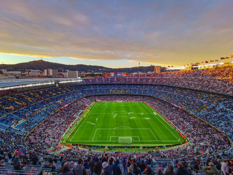 Aerial view of Camp Nou stadium filled with spectators during a football match at sunset in Barcelona, Spain.