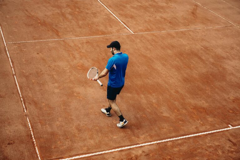 Athlete holding tennis racket on a clay court, summer sports action