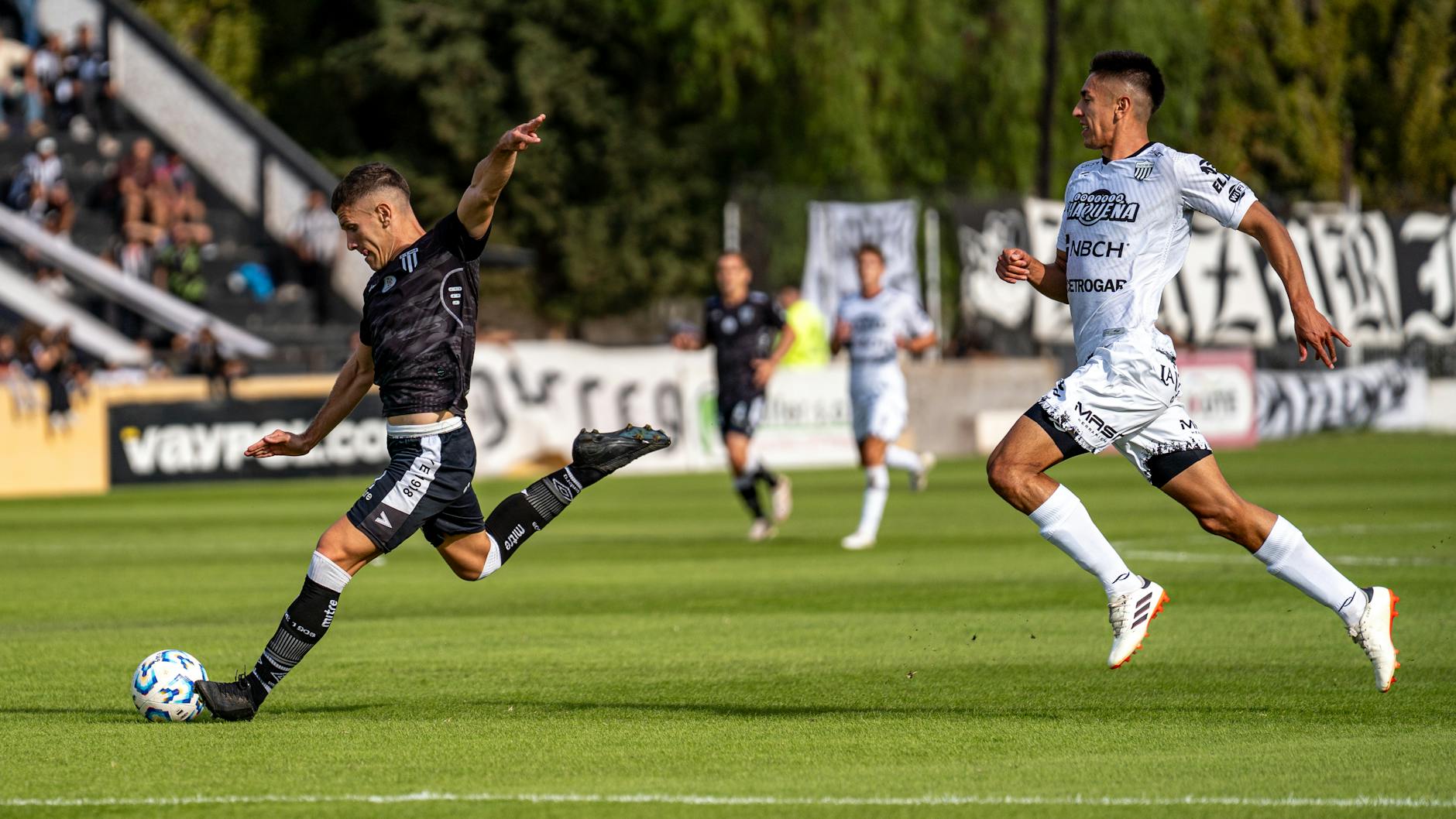 Dynamic scene of soccer players in action during a competitive match on a bright day.