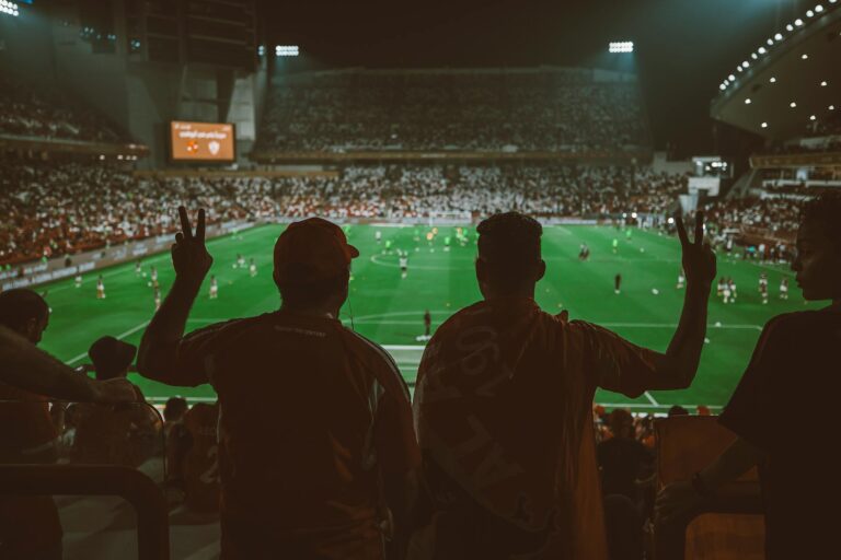 A vibrant football match with fans cheering in an illuminated stadium.
