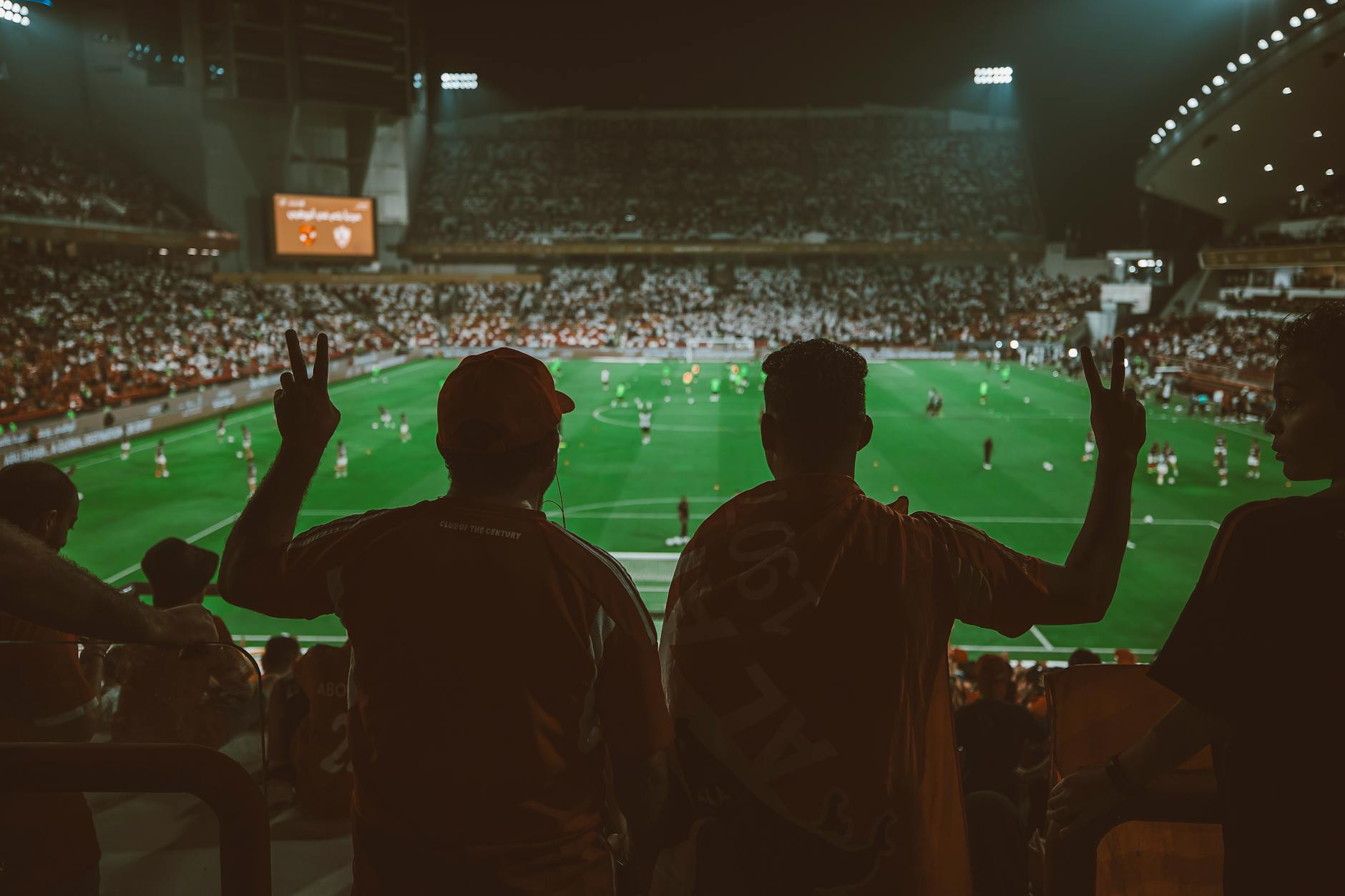 A vibrant football match with fans cheering in an illuminated stadium.