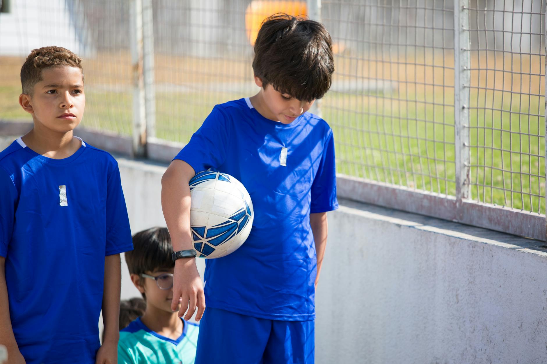 A group of boys in blue uniforms preparing for a soccer game outdoors.