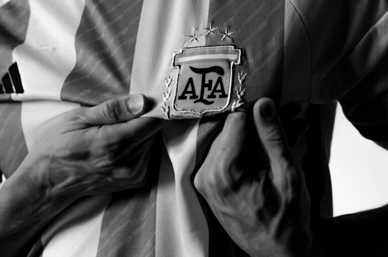 A close-up view of hands holding the Argentina football jersey with AFA emblem, in black and white.