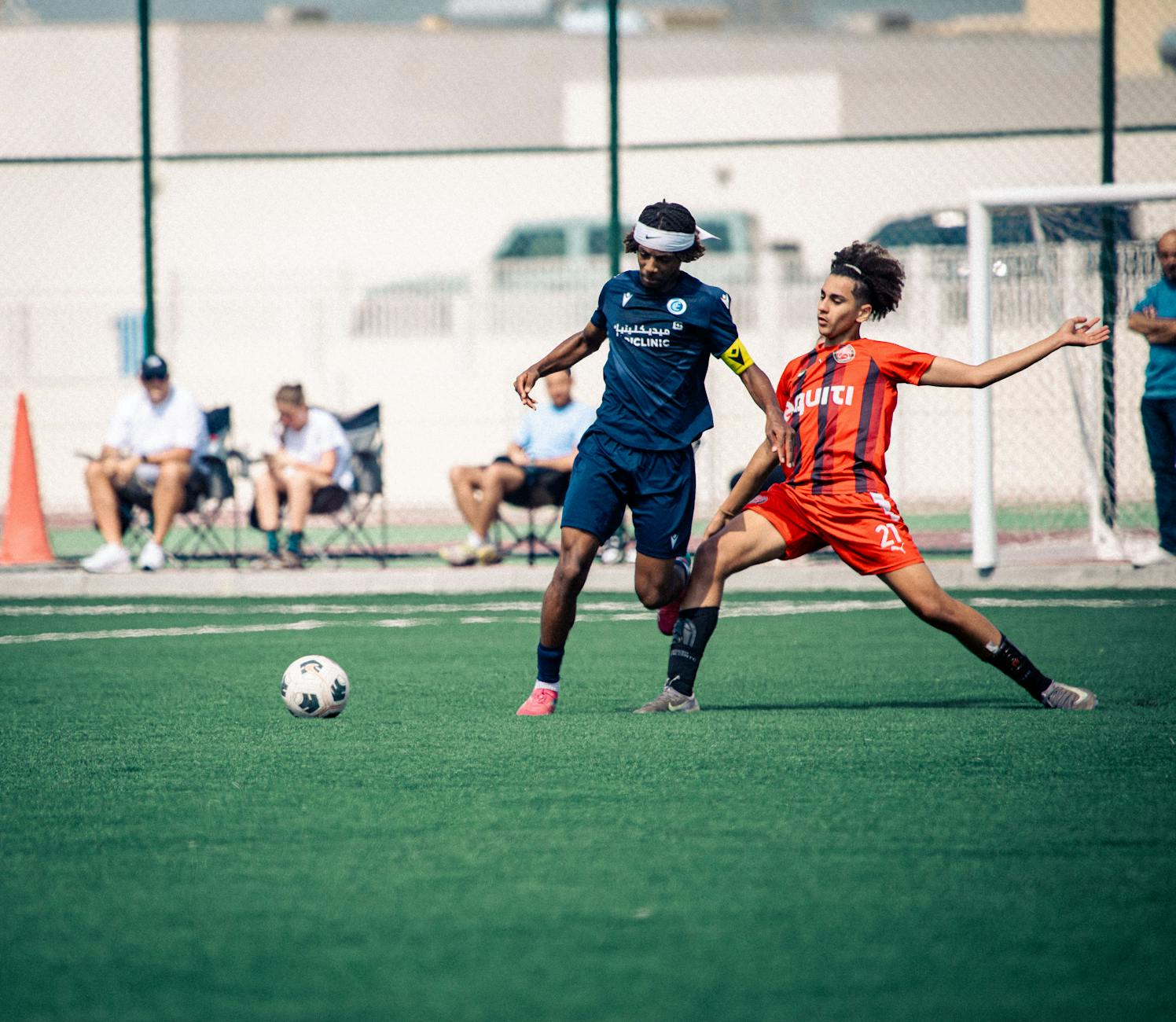 A dynamic moment in an outdoor soccer match with two players in action, competing for the ball.