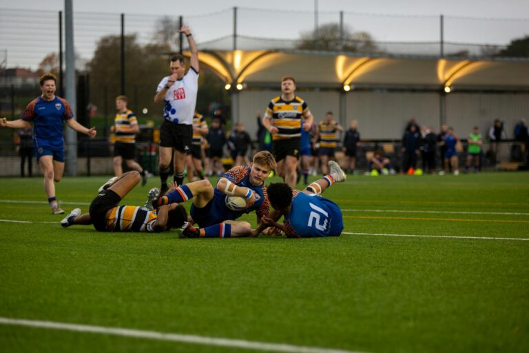 Intense action during a university rugby match on a green field.