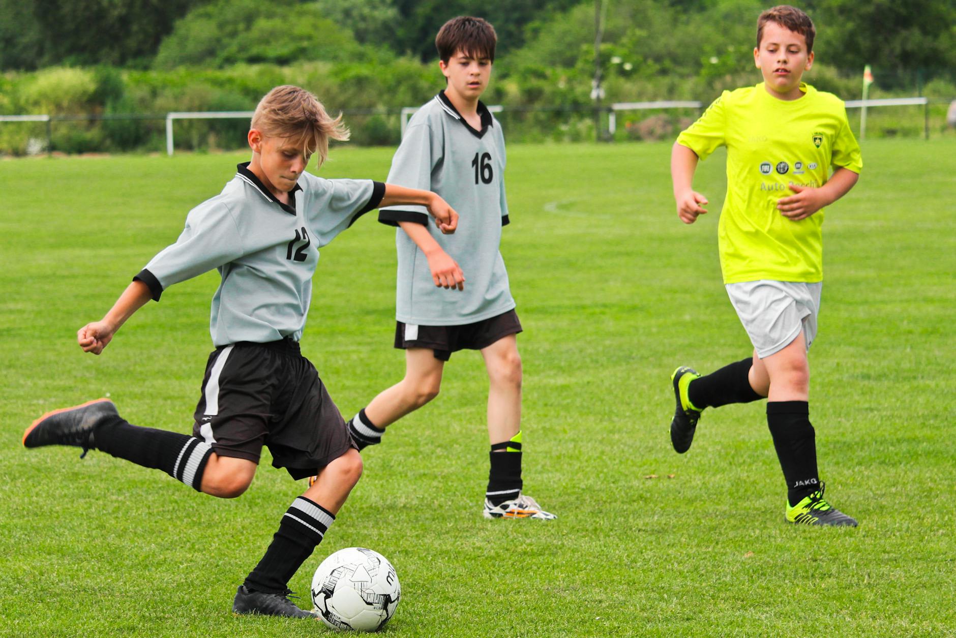 Young boys engage in a thrilling soccer match on a green field, showcasing teamwork and skill.