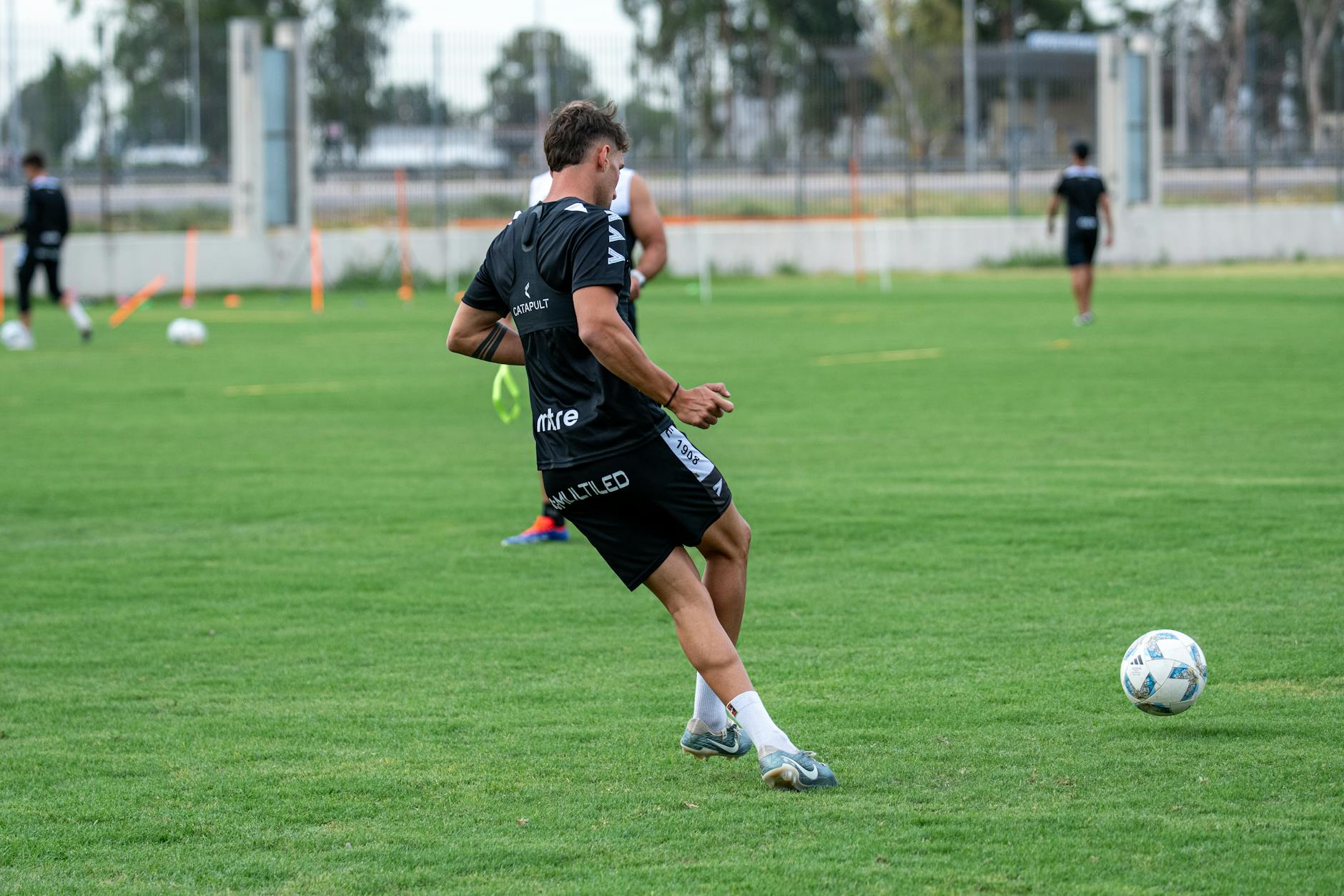 A male soccer player practices on an outdoor field during the day.