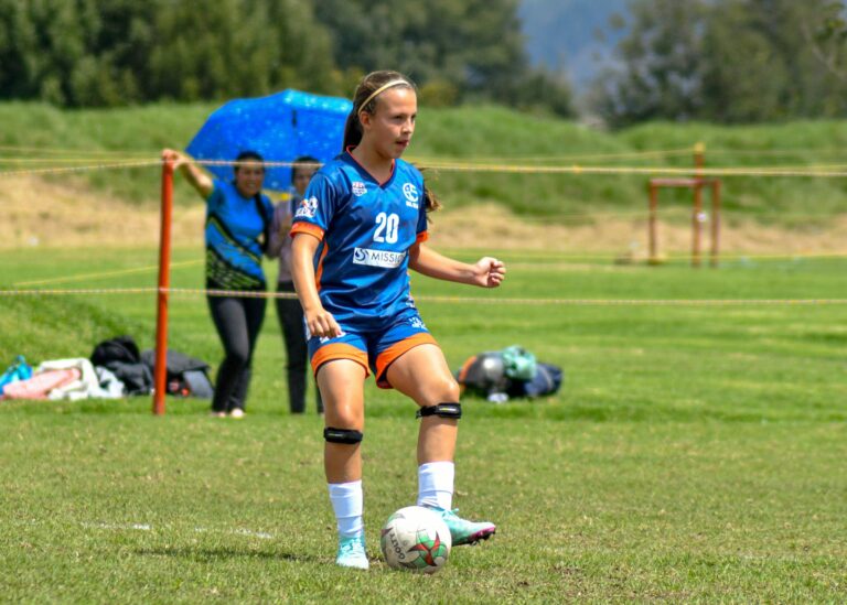 Teen girl playing soccer on a sunny day, showcasing determination and athleticism.