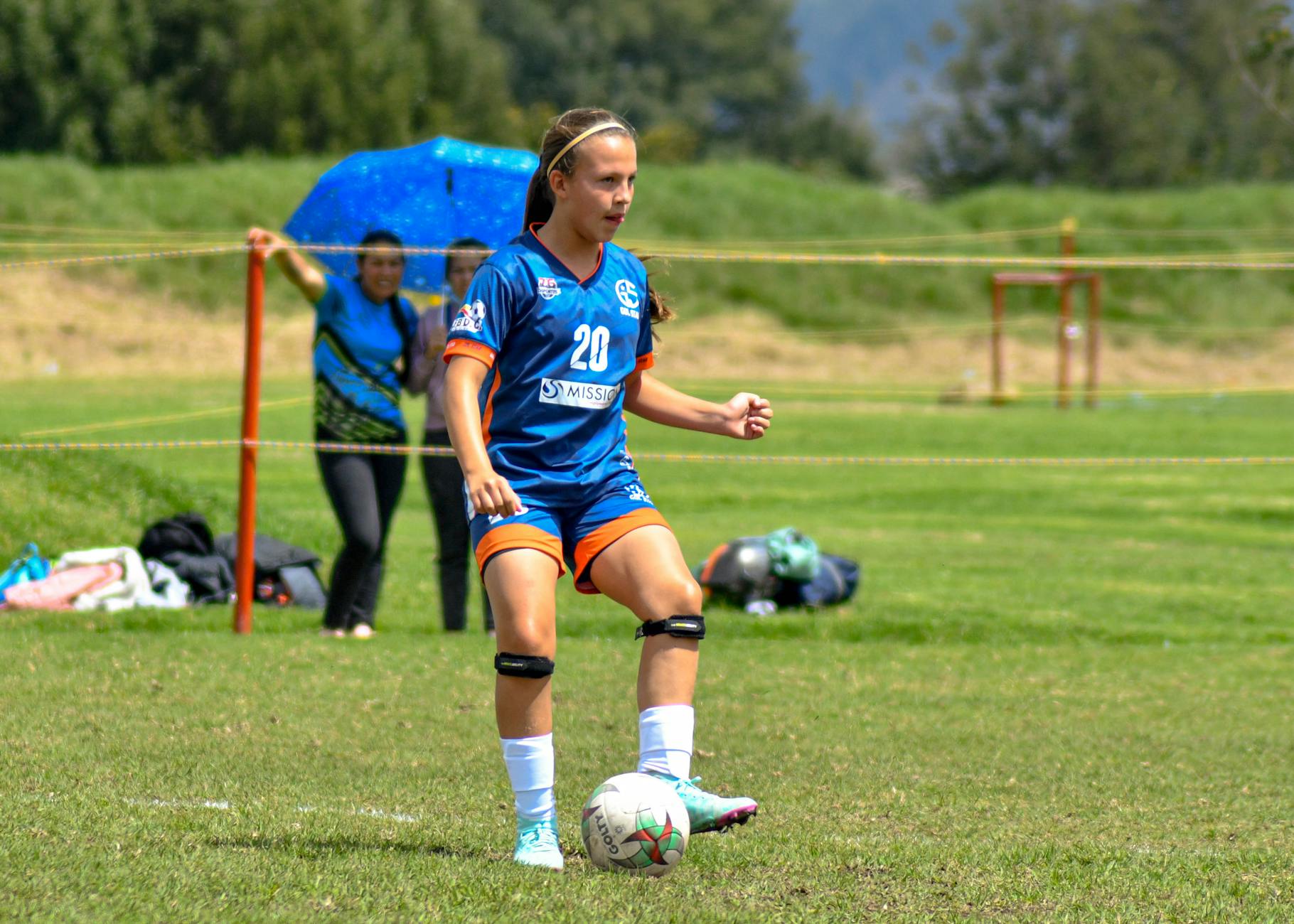 Teen girl playing soccer on a sunny day, showcasing determination and athleticism.