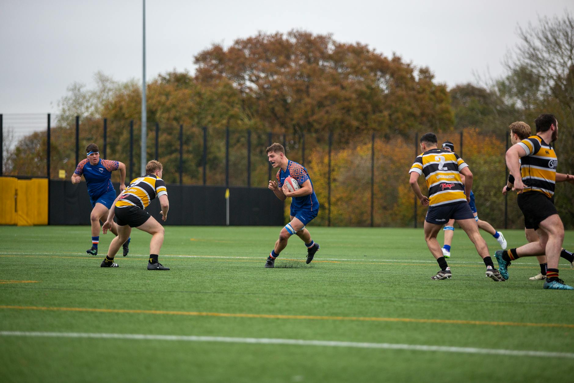 Action-packed university rugby match on a vibrant fall day.