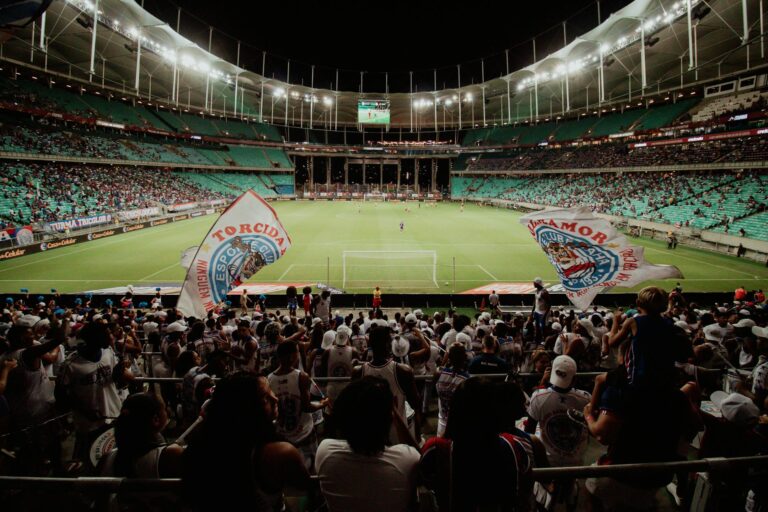 Energetic soccer fans cheer during a night match at a large stadium, creating an exciting atmosphere.
