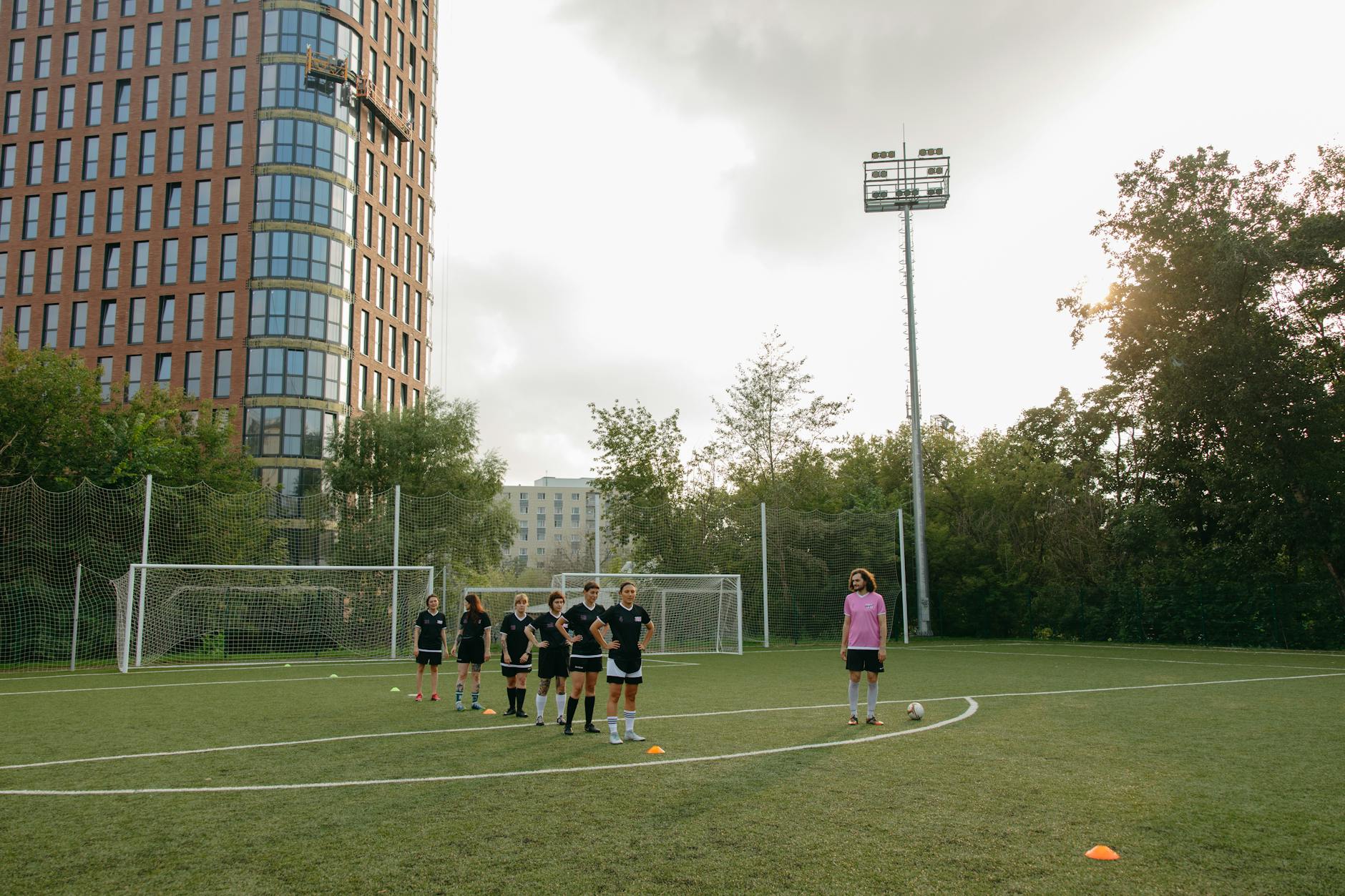 Female athletes training on a soccer field with focus on teamwork and coaching outdoors.