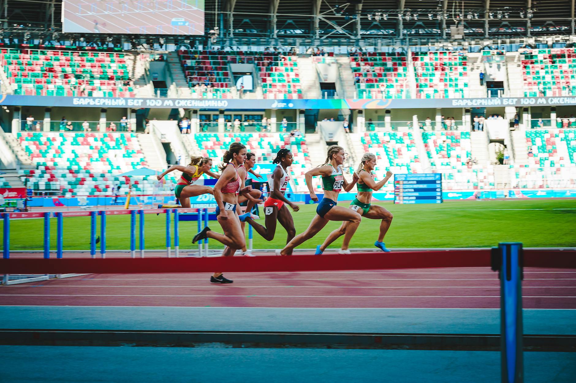 Athletes compete in an intense women's hurdles event at Minsk stadium, showcasing speed and agility.