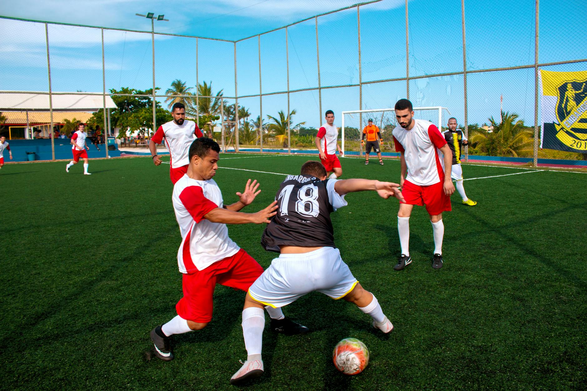 Athletes on an outdoor soccer field competing in an intense match under a clear sky.
