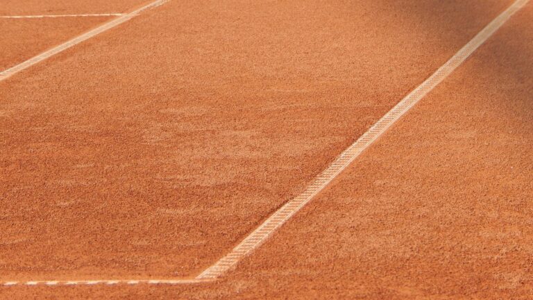 Close-up of a clay tennis court highlighting the detailed white line pattern.
