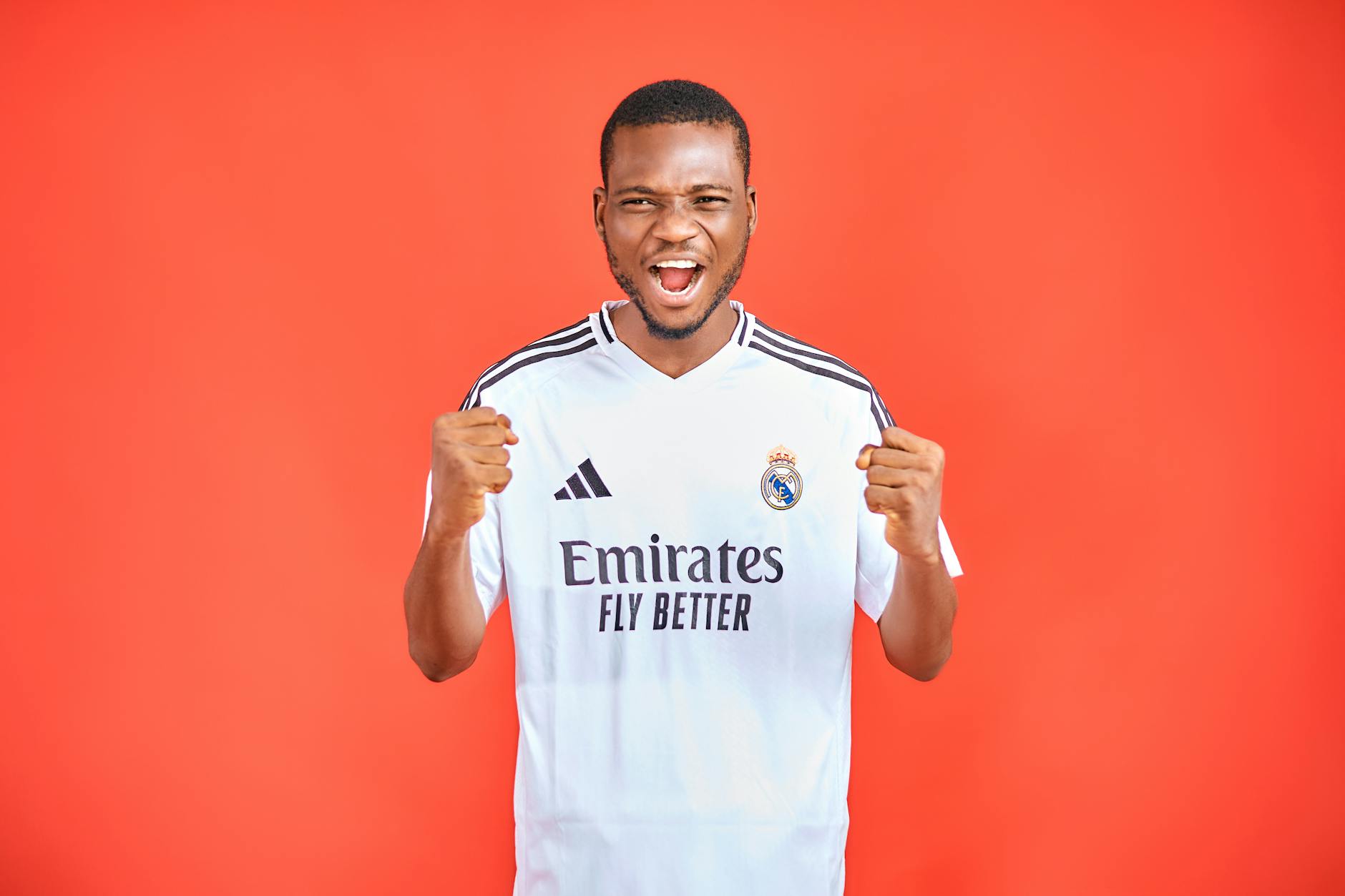Energetic soccer fan in a team jersey cheering against a vibrant red background.