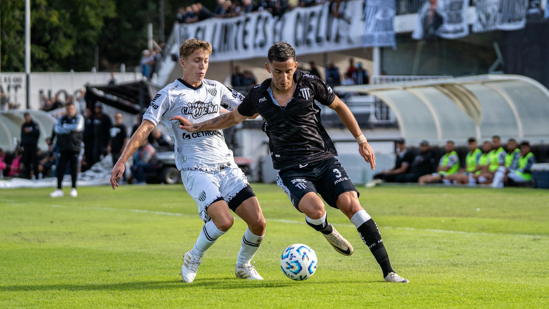 Two soccer players competing fiercely during a match on a sunny day.