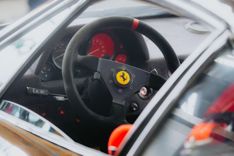 Detailed shot of a classic car steering wheel showcasing iconic design and vintage appeal.