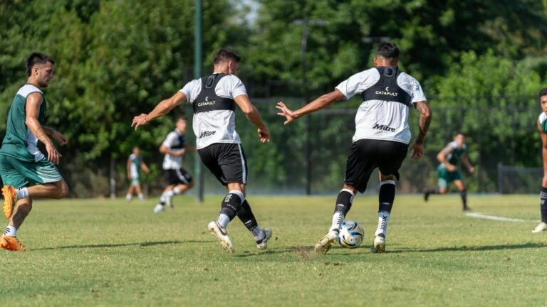 Soccer players training on a sunny day, focusing on teamwork and fitness with vibrant green surroundings.