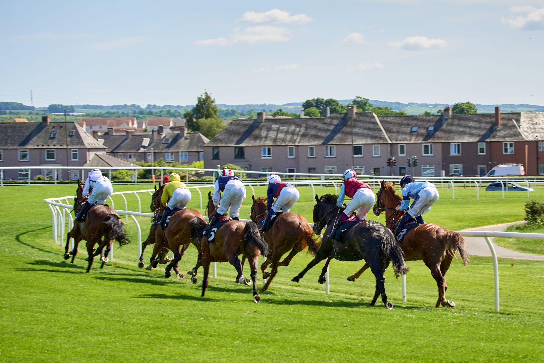 Dynamic shot of a horse race in Musselburgh with jockeys in colorful attire.