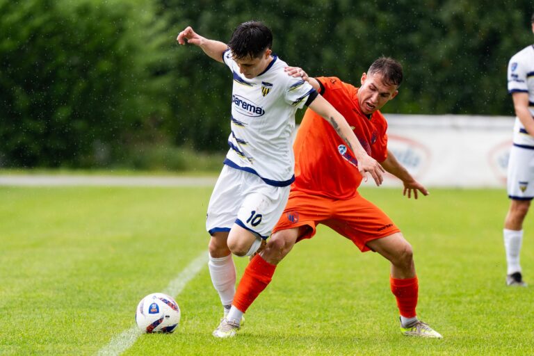 Two soccer players compete intensely during a match on a rainy day.